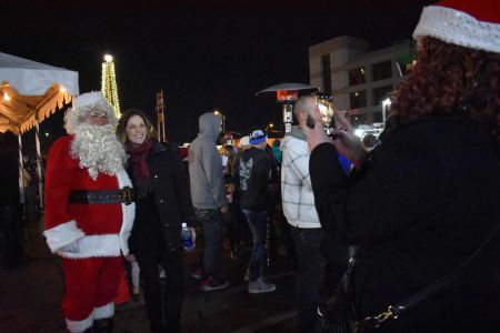 santa poses with a girl while another girl takes a photo