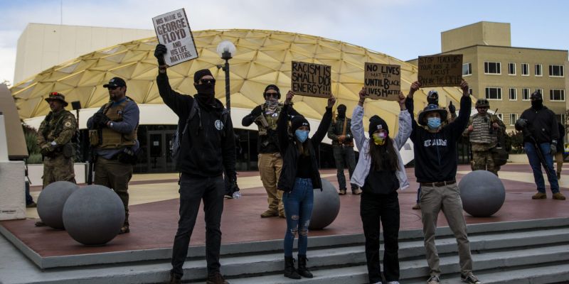 Los manifestantes de Las Vidas Negras Importan sostienen carteles frente a los Three Percenters que se estacionaron afuera del Pioneer Center el 7 de junio de 2020 durante una vigilia pacífica en el centro de Reno.