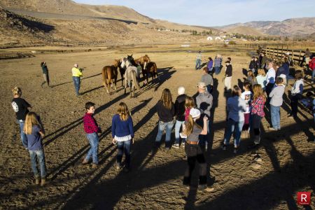 Clinic participants gather in a field near several horses.