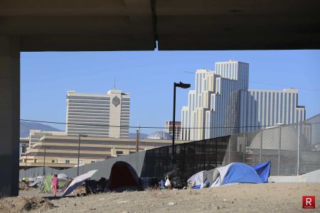 A homeless encampment with the Reno city skyline behind it.