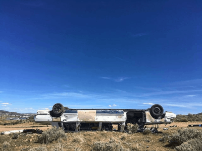 An upside down junk car in the desert