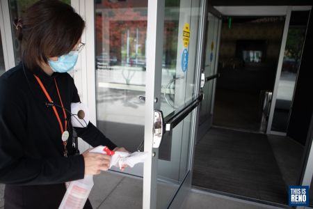 A staff members sanitizes the entry of the Nevada Museum of Art as it reopens. Image: Isaac Hoops
