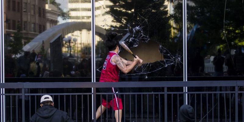 A rioter breaks windows at City Hall. Image: Ty O'Neil
